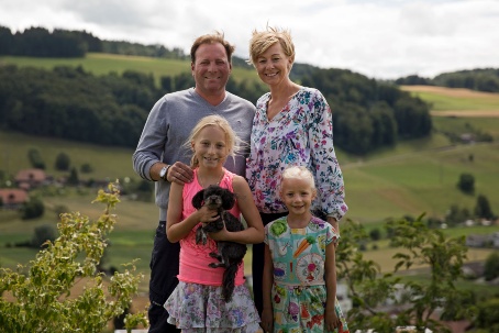Die Familie Spycher mit ihren beiden kleinen Kindern und einem Hündchen vor idyllischer Landschaft